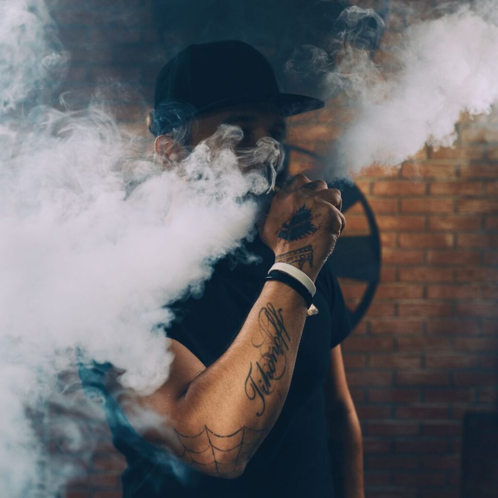 Man vaping in front of a brick wall